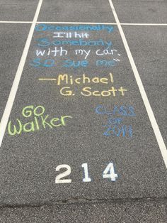 a parking lot with chalk writing on the asphalt and numbers painted on it in different colors