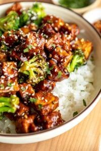 a bowl filled with rice and broccoli covered in sauce