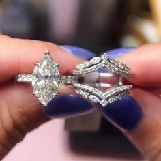 a woman's hand holding an engagement ring with two diamonds on the top and bottom