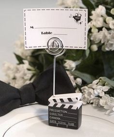 a white plate topped with a clapa board and a black bow tie on top of it