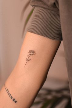 a woman's arm with a single rose tattoo on the left side of her arm