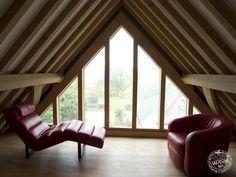 two red leather chairs sitting in front of a large window with wooden beams on the ceiling