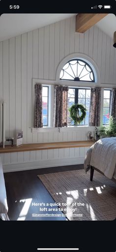 there is a bedroom with white walls and wood flooring on the wall, along with a large window