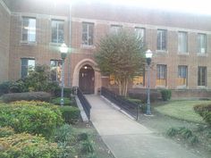 a brick building with trees and bushes around it