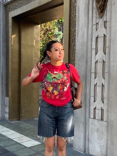 a woman standing in front of a building with her hand on her hip and looking up at the sky