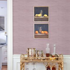 a gold bar cart in a kitchen with two pictures on the wall above it and glasses