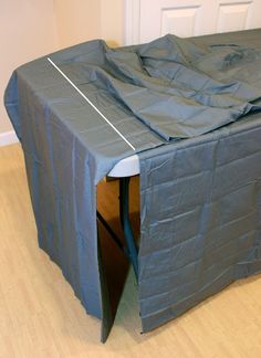 a table covered with blue tarp sitting on top of a hard wood floor next to a white door