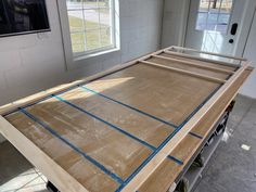 an unfinished bed frame in the middle of a room with windows and other items on the floor