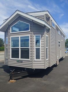 a tiny house sitting in the middle of a parking lot next to a building with windows