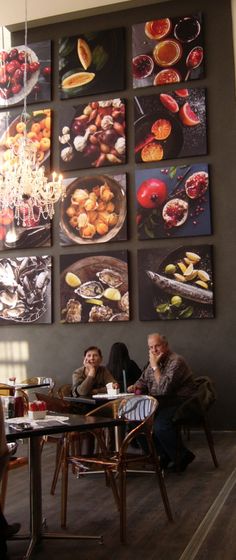 three people sitting at a table in front of pictures on the wall