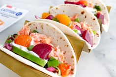 three tortillas filled with shrimp and veggies sitting on a counter top