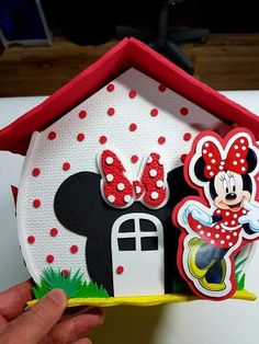 someone is holding up a paper house with minnie mouse decorations on the front and side