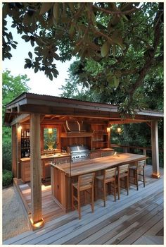 an outdoor kitchen and dining area is lit up by lights on the outside decking