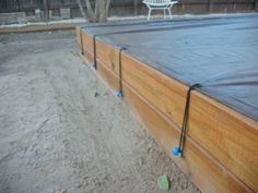 a large wooden pool in the middle of a yard with plastic covering on it's sides