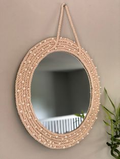 a round mirror hanging on the wall next to a potted plant