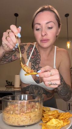 a woman eating food from a bowl on top of a white plate next to some chips