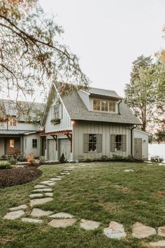 a white house sitting on top of a lush green field next to a lake and trees