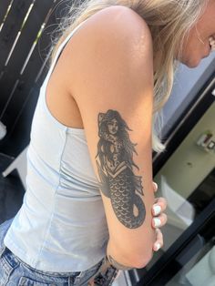 a woman with a mermaid tattoo on her arm