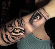 a woman's arm with an eye and tiger tattoo on the left side of her arm