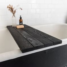 a bath tub with a wooden shelf next to it and a bottle on the edge