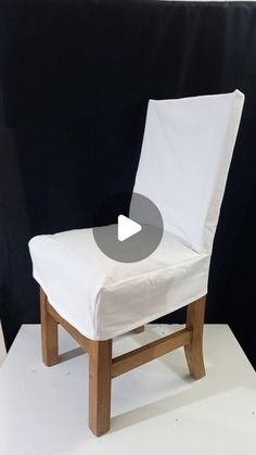 a white chair sitting on top of a white floor next to a black wall in front of a black backdrop