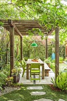 an outdoor dining area with green chairs and a wooden pergolan on the ground