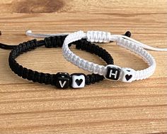 two black and white bracelets with hearts on them sitting on top of a wooden table