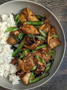 a bowl filled with rice and meat on top of a wooden table