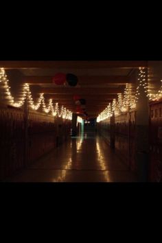 the hallway is lit up with christmas lights and garlands on the ceiling, along with several lockers