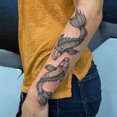 a woman's arm with two fish tattoos on it