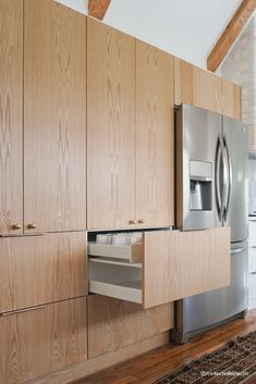 a kitchen with wooden cabinets and stainless steel refrigerator freezer in the center, on hardwood flooring