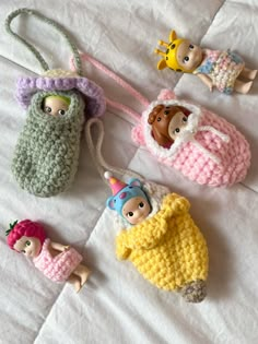 four crocheted toy purses are laying on a white sheet and one is holding a doll