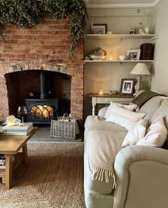 a living room filled with furniture and a fire place next to a brick wall covered in greenery