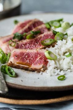 a plate with rice, meat and green onions on it