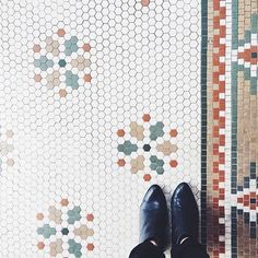 a person wearing black shoes standing in front of a tiled floor with hexagonal tiles