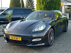 a black sports car is parked in front of some bushes and cars on the street