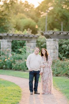 an engaged couple walking down a path at sunset