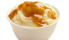 a white bowl filled with mashed potatoes covered in caramel sauce