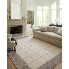 a living room filled with furniture and a large rug on the floor in front of a fire place