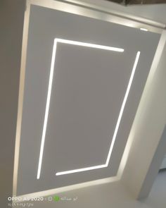 an empty room with white walls and a square shaped light fixture in the center that is lit up