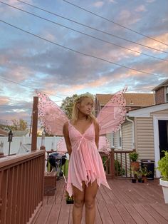 a woman in a pink fairy costume standing on a deck