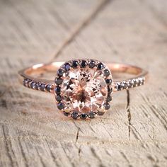 an engagement ring with a pink diamond surrounded by black and white diamonds on a piece of wood