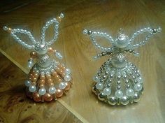 two decorative angel ornaments sitting on top of a wooden table