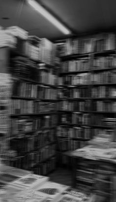 black and white photograph of stacks of books in a book store with blurry background