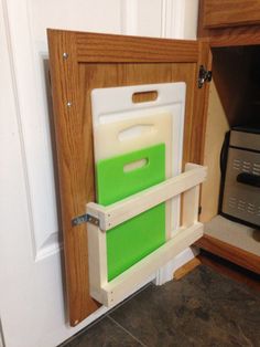 a kitchen cabinet door is open to reveal a cutting board