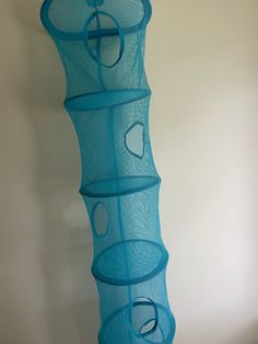 there is a blue vase that has circles on the bottom and sides, hanging from a white wall