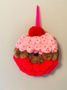 a stuffed animal hanging from the side of a wall with a pink hat on it's head