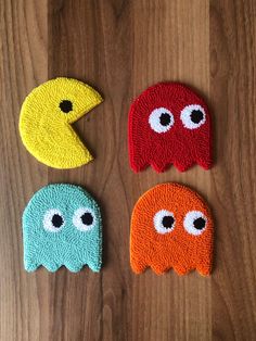 four different colored bath mitts with googly eyes on top of a wooden surface