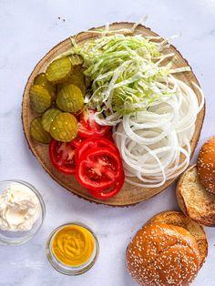 an assortment of vegetables on a plate with bread and dipping sauces next to it