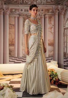 Step into glamour with this exquisite gray sari, crafted from luxurious sequined fabric. The heavy skirt provides a stunning foundation, while the draped pallu is fully embroidered, featuring beautiful long tassels that add a playful touch. The padded blouse ensures a flattering fit, making this ensemble perfect for grand occasions where elegance and sophistication are essential. Embrace the allure of this captivating outfit, designed to make a lasting impression. Diwali Silver Pre-draped Saree With Mirror Work, Silver Embellished Sharara For Party, Silver Pre-draped Saree With Zari Work For Festive Occasion, Silver Semi-stitched Pre-draped Saree For Designer Wear, Designer Silver Sharara For Festivals, Designer Silver Sharara For Festive Occasions, Silver Bollywood Pre-draped Saree For Festive Occasions, Traditional Silver Blouse Piece With Mirror Work, Elegant Silver Saree With Mirror Work